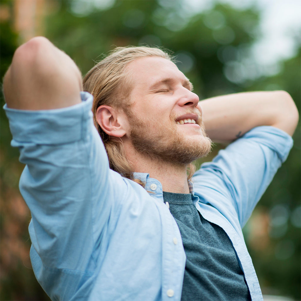 Man enjoying a moment of relaxation outdoors with a smile, representing comfort and wellness.