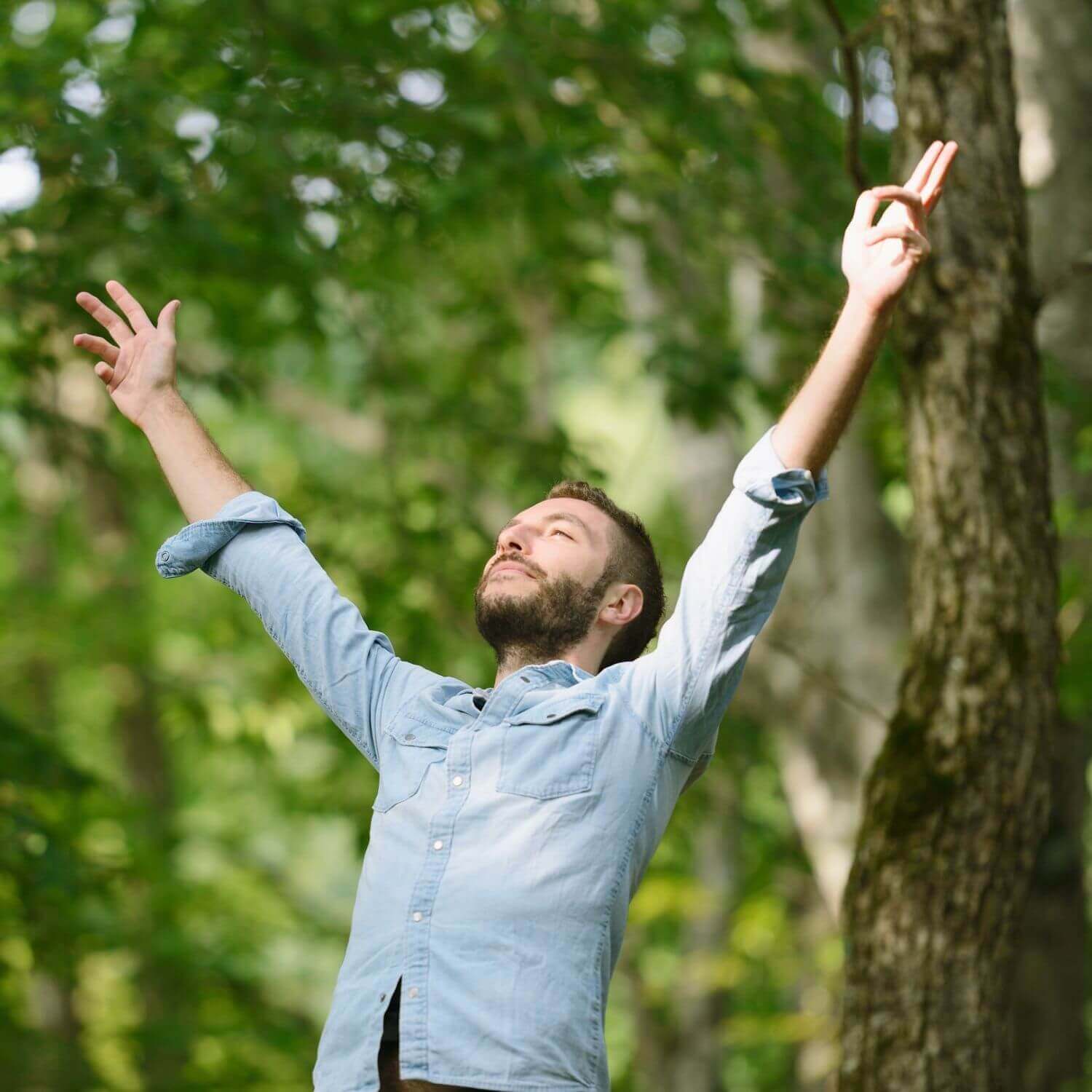 Man enjoying nature with arms raised, conveying a sense of freedom and vitality in the outdoors.