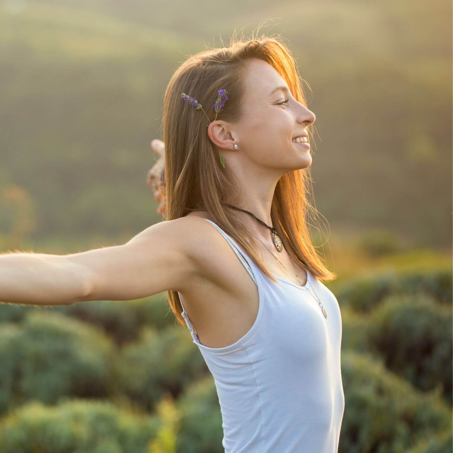 Woman enjoying nature with arms outstretched, embodying freshness and calm, symbolizing wellness.