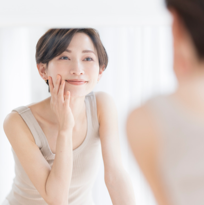 Woman applying Organic Relief Essence for a clean, healthy skin appearance in a bright setting.