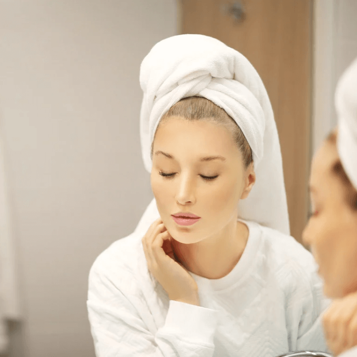 Woman applying skincare with Ultra Acupoint Patch after shower, showcasing a refined skin appearance.