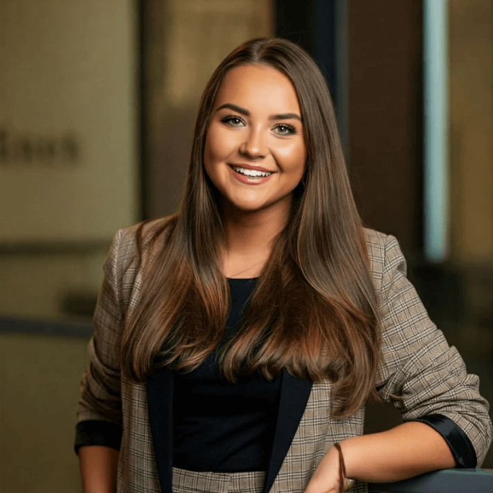 Smiling woman with long hair in a blazer, representing confidence and approachability in a professional setting.