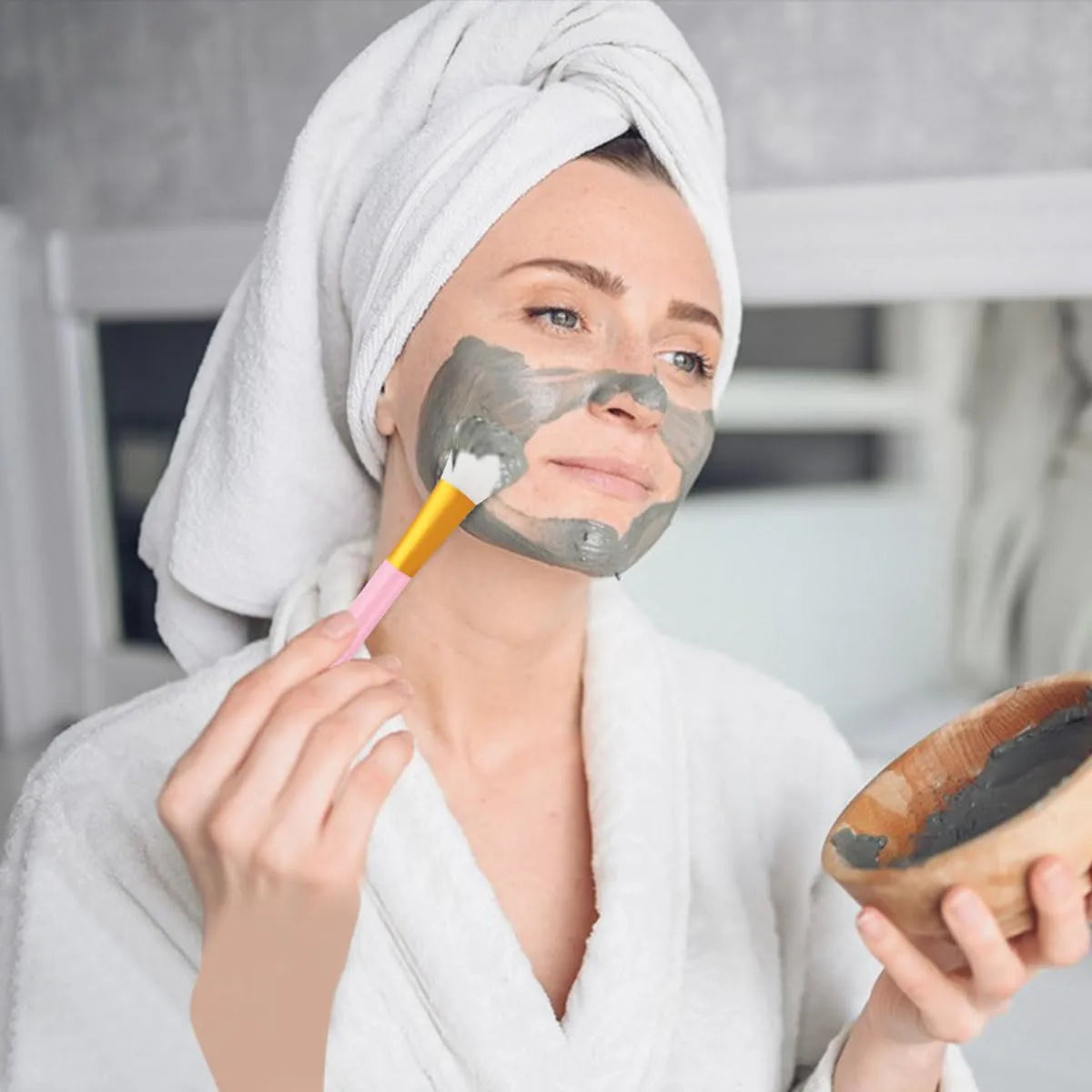 Woman using a 2-Piece Silicone Face Mask Applicator Brush Set to apply a face mask.