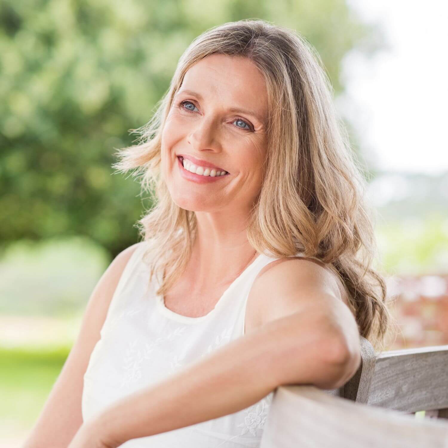 Smiling woman enjoying outdoor relaxation with smooth skin, representing the benefits of Skin Restore Nano Patch.